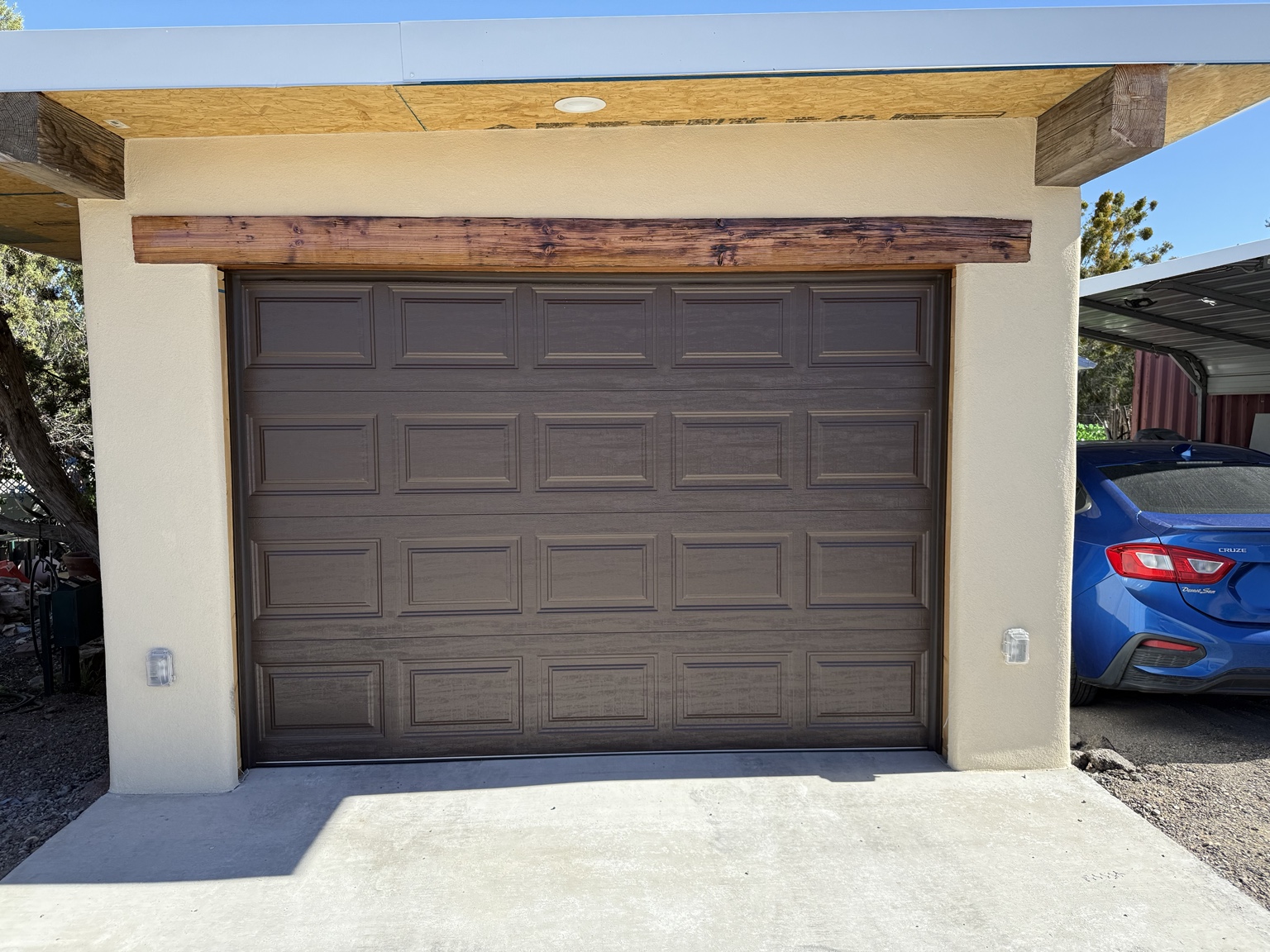 Brown raised-panel garage door installed on a stucco garage