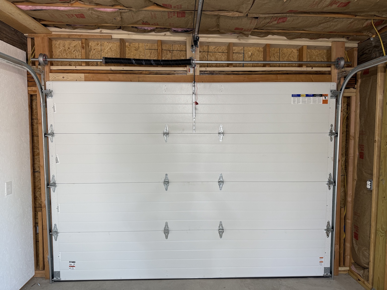 Interior of installed garage door showing hinges, tracks and torsion spring