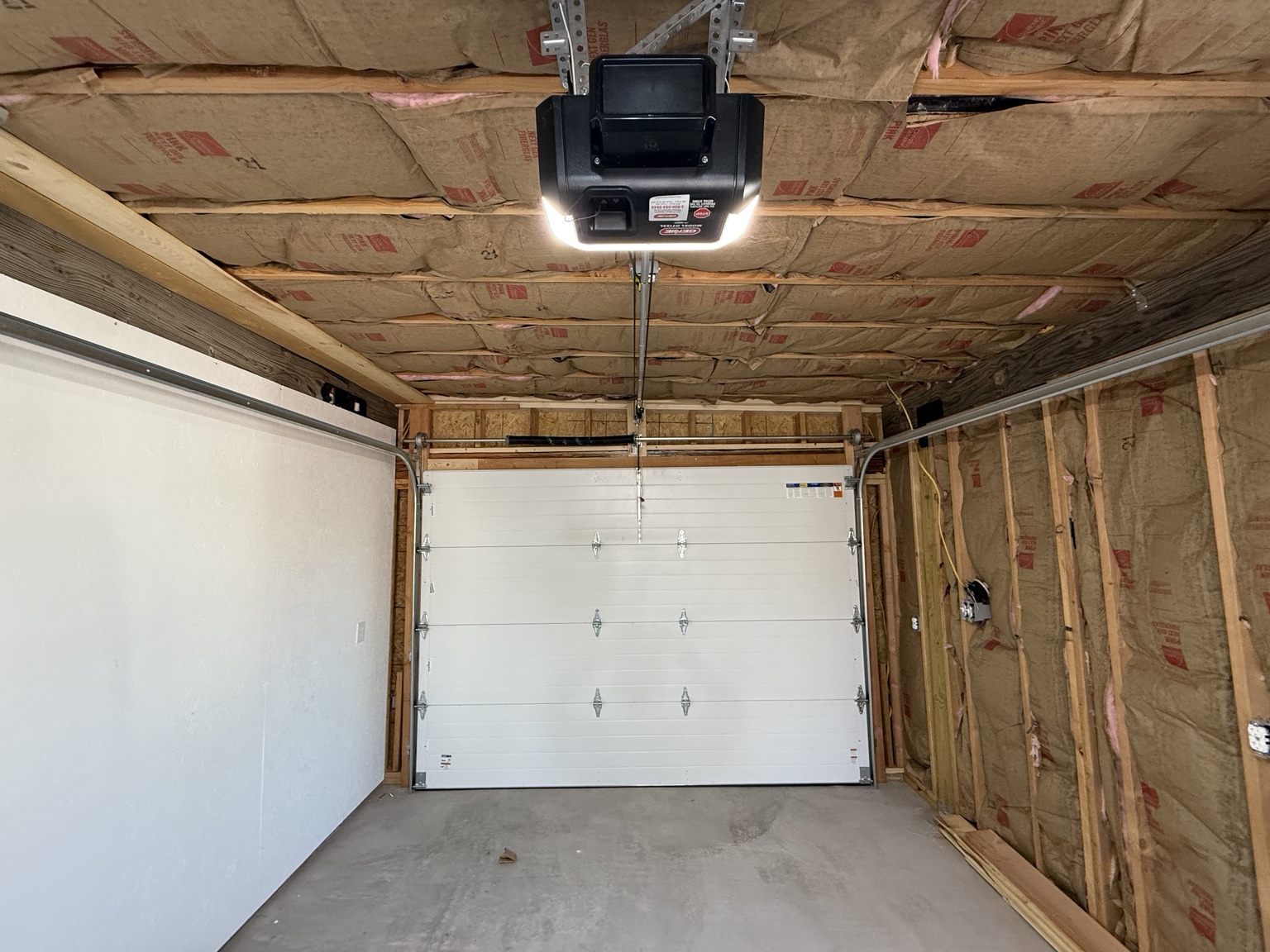 Garage interior with installed sectional door and ceiling-mounted opener