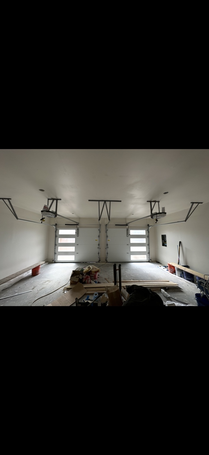 Interior view of two garage doors with vertical windows and overhead openers