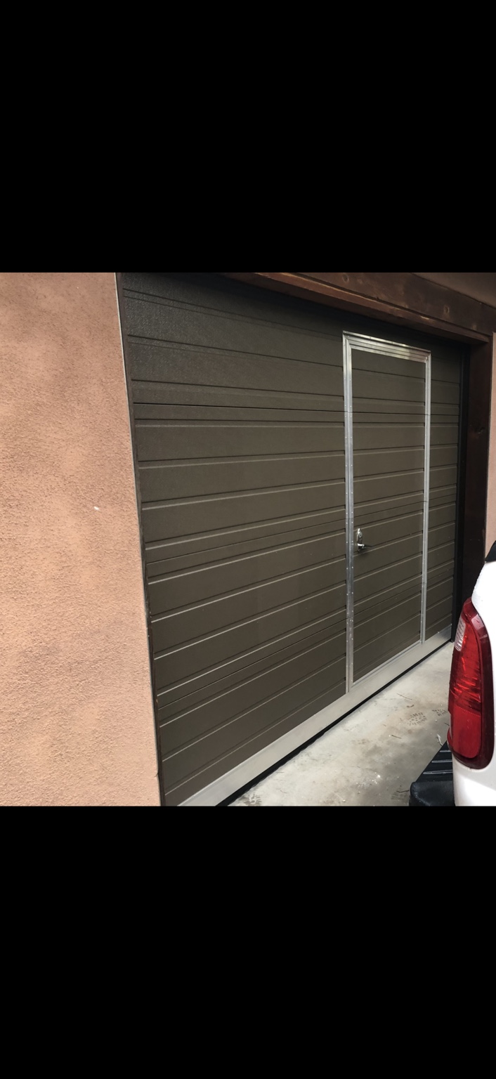 Exterior view of a brown garage door with an integrated pedestrian door